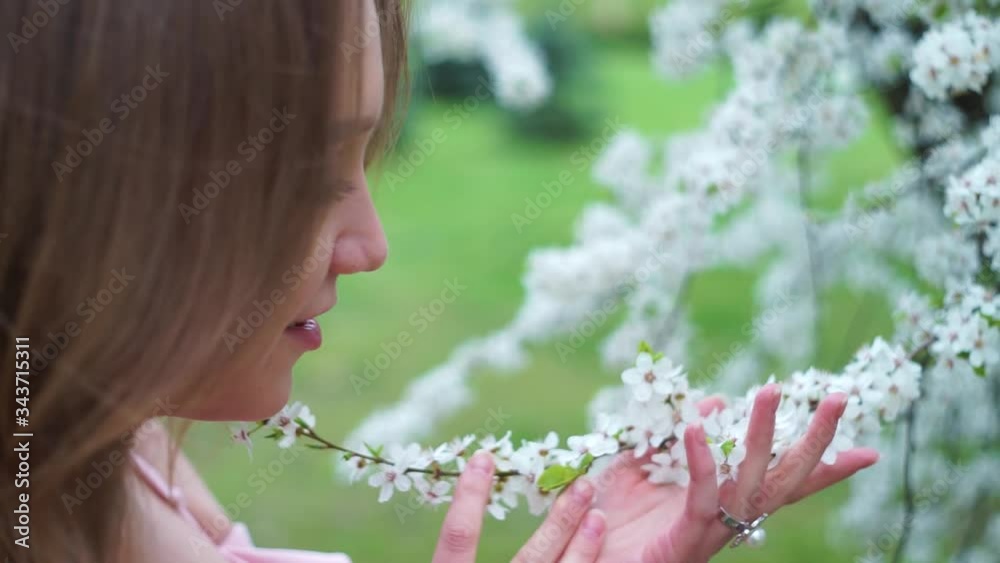 Close up portrait of tender girl in a white blouse under a blossoming cherry tree with flowers. Close up portrait of tender girl in a white blouse under a blossoming cherry tree with flowers.