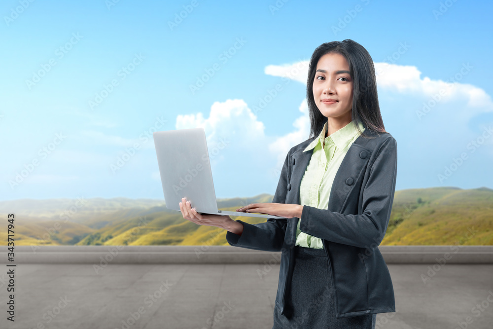 Asian businesswoman standing while using a laptop working remotely Asian businesswoman standing while using a laptop working remotely