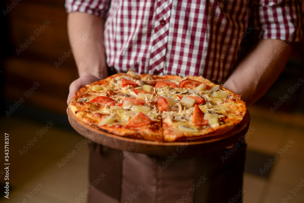 A waiter holds a plate of tasty food. Italian cuisine in restaurant, Delicious pizza with spinach, olives and mushrooms A waiter holds a plate of tasty food. Italian cuisine in restaurant, Delicious pizza with spinach, olives and mushrooms