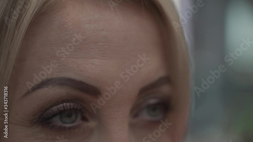 Close up of green eyes of mid aged blond women with a powerfull gripping thrilling dramatic scary look like ready to fight