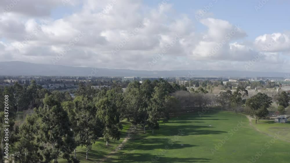Aerial drone flight left above green grass and trees in suburban landscape Aerial drone flight left above green grass and trees in suburban landscape