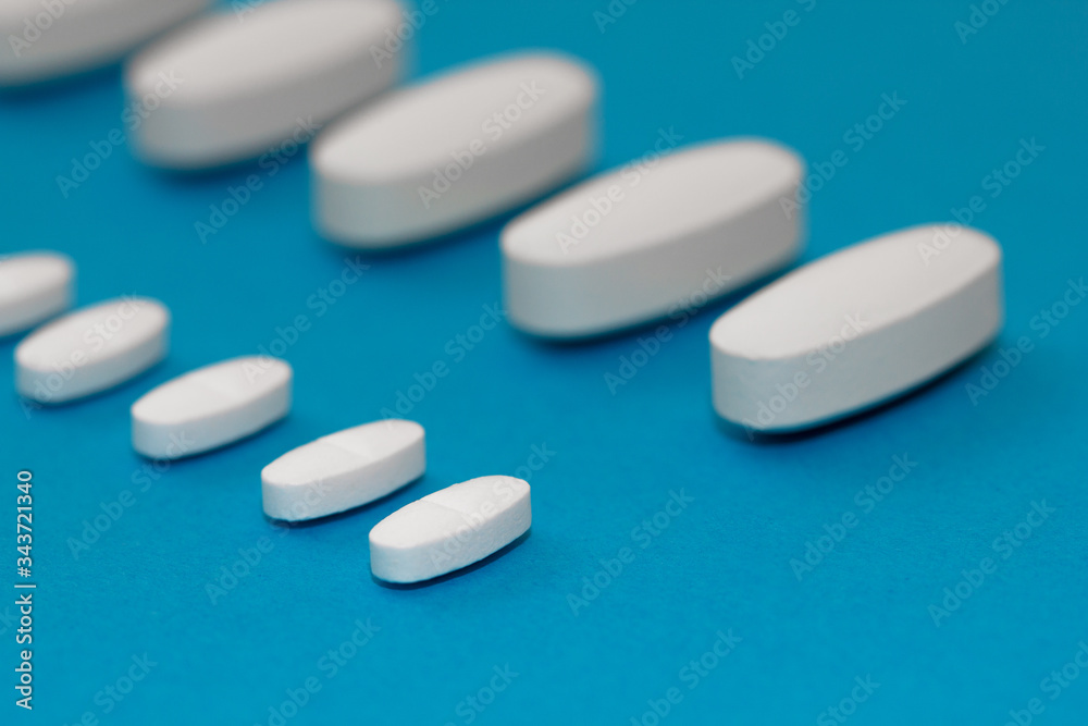 White tablets on a blue background close-up. Macro pills. Medical care for flu and colds. Protection from Covid19