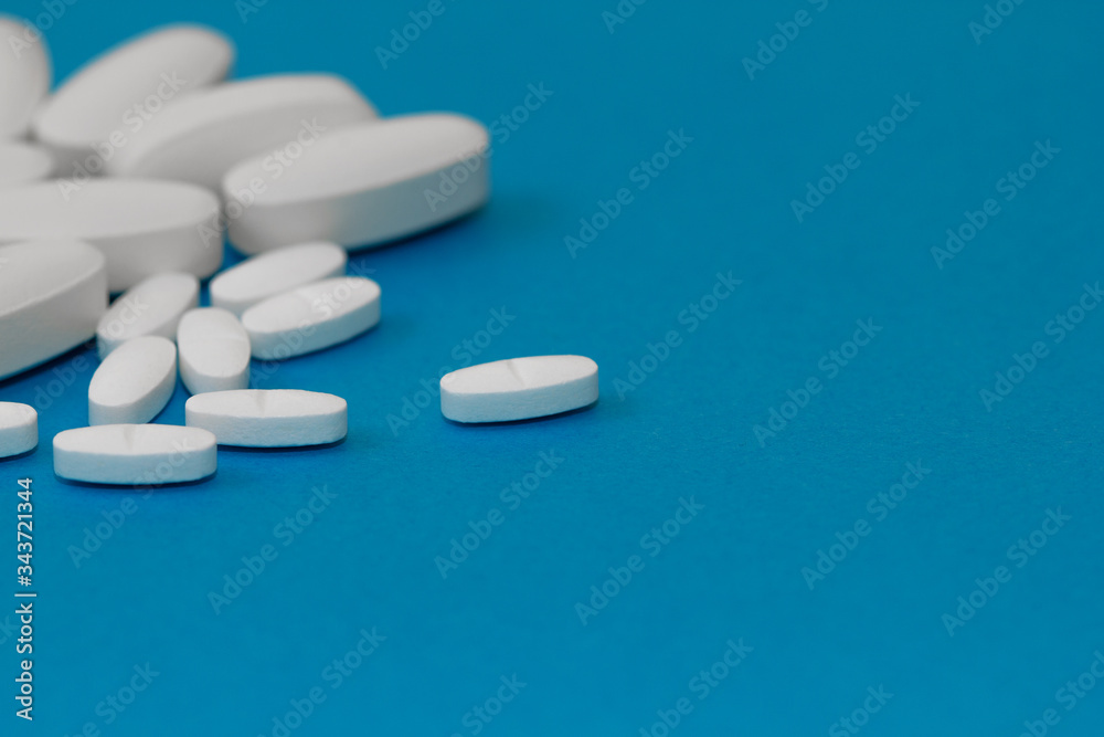 White tablets on a blue background close-up. Macro pills. Medical care for flu and colds. Protection from Covid19
