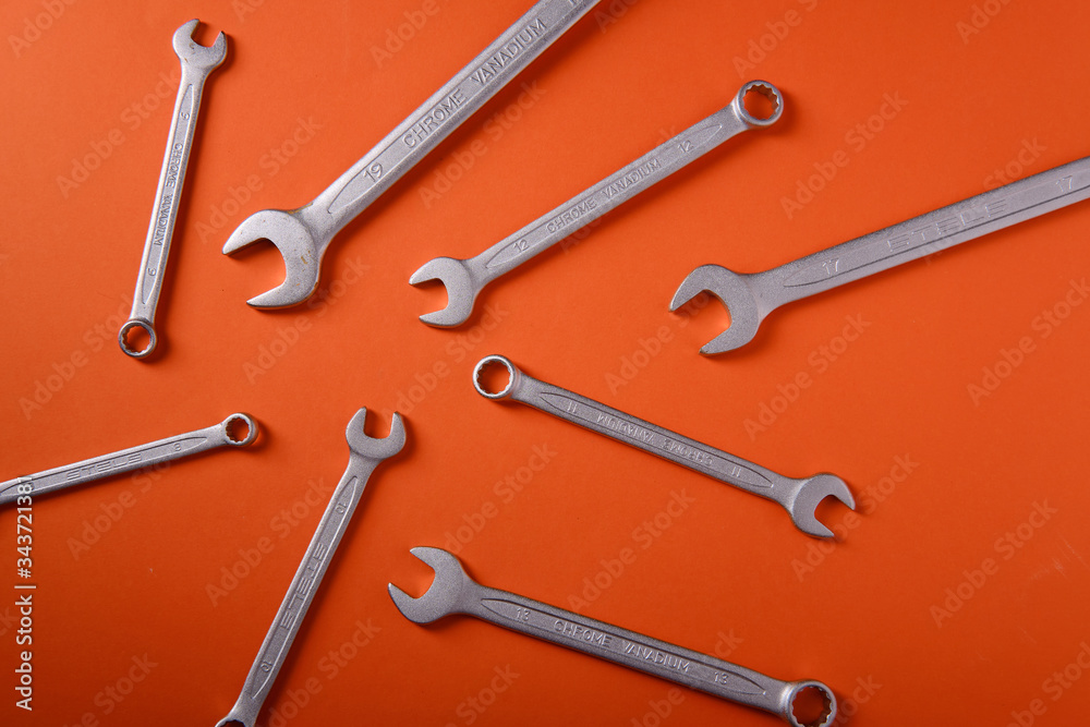 Steel wrenches on an orange background, top view Steel wrenches on an orange background, top view