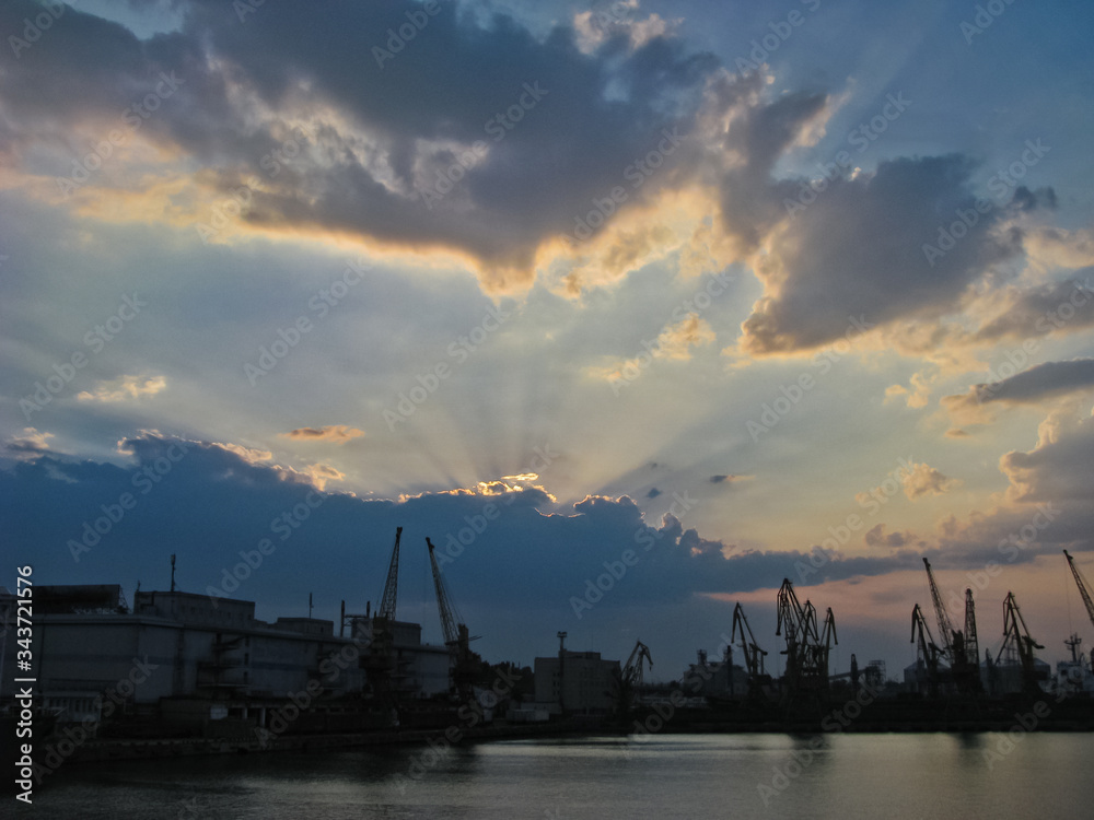Naklejka premium The Rays of the Setting Sun Break Through the Clouds and Precede Twilight