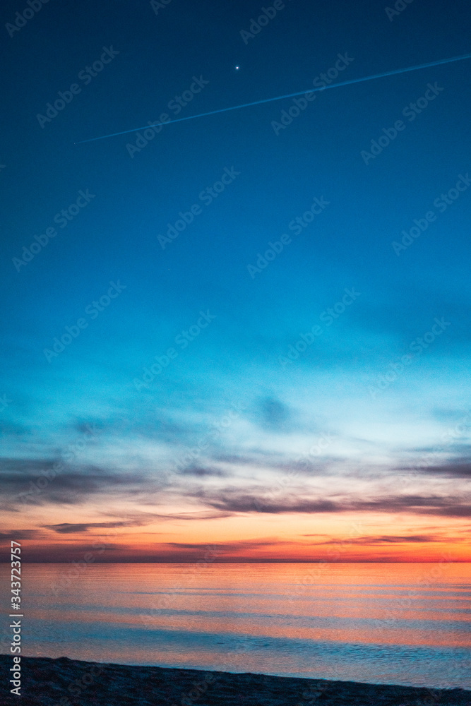 colorful sunset by the sea with a first star visible