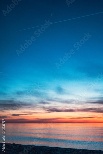 colorful sunset by the sea with a first star visible © Radosaw