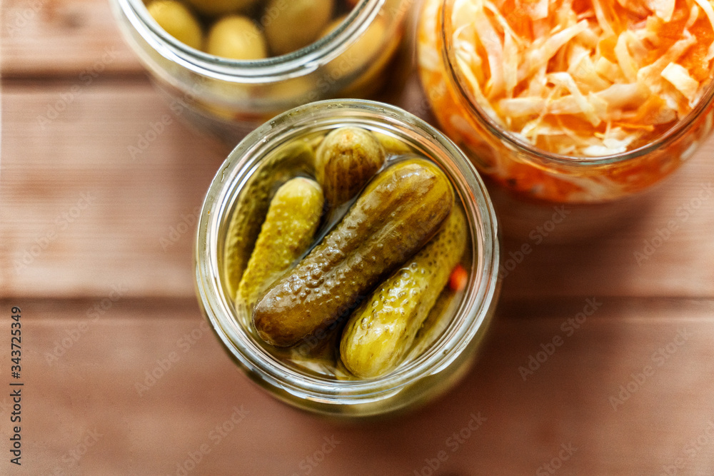 Various pickled snacks in cans, cucumber pickles, salted cabbage and olives. On a wooden table. View from above Various pickled snacks in cans, cucumber pickles, salted cabbage and olives. On a wooden table. View from above