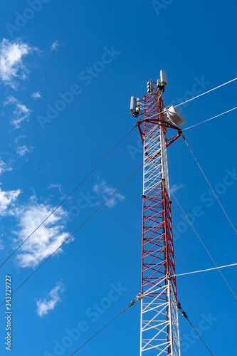 Phone tower antenna with blue sky and cloud background