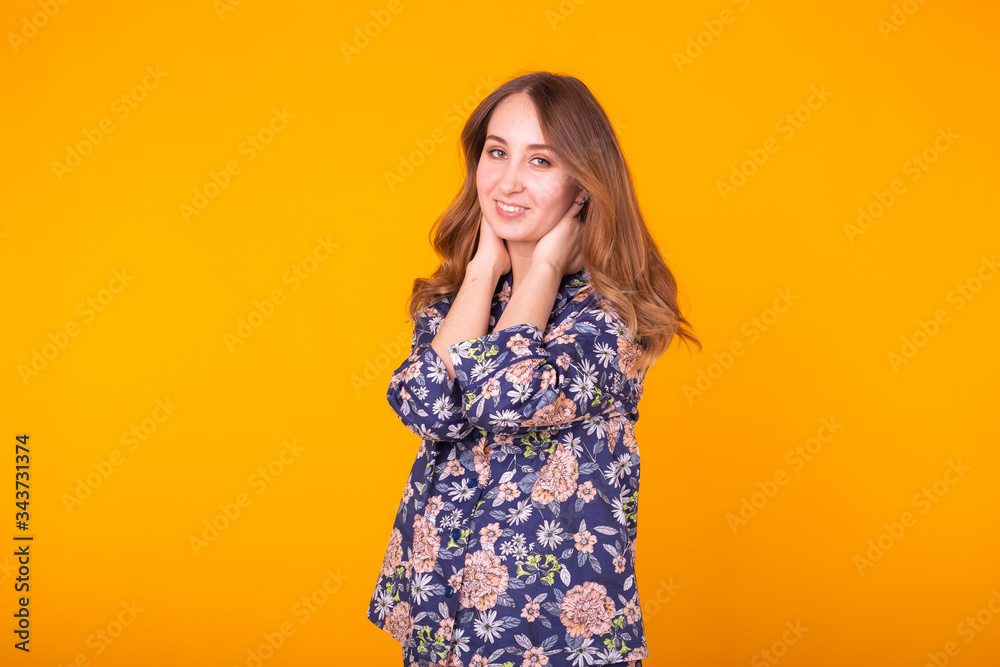 Cute and cheerful woman in home wear pajama studio lifestyle yellow background emotions.