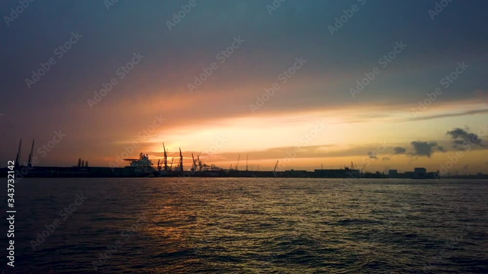 Sunset on a harbour overlooking the water on a calm day. Rotterdam Harbour riverside Sunset on a harbour overlooking the water on a calm day. Rotterdam Harbour riverside