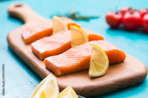 Delicious salmon steak on wooden cutting board, close-up.