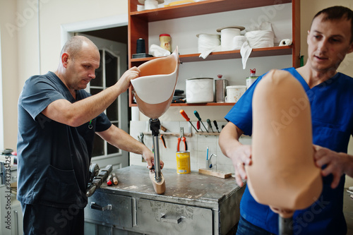 Two prosthetist man workers making prosthetic leg while working in laboratory.