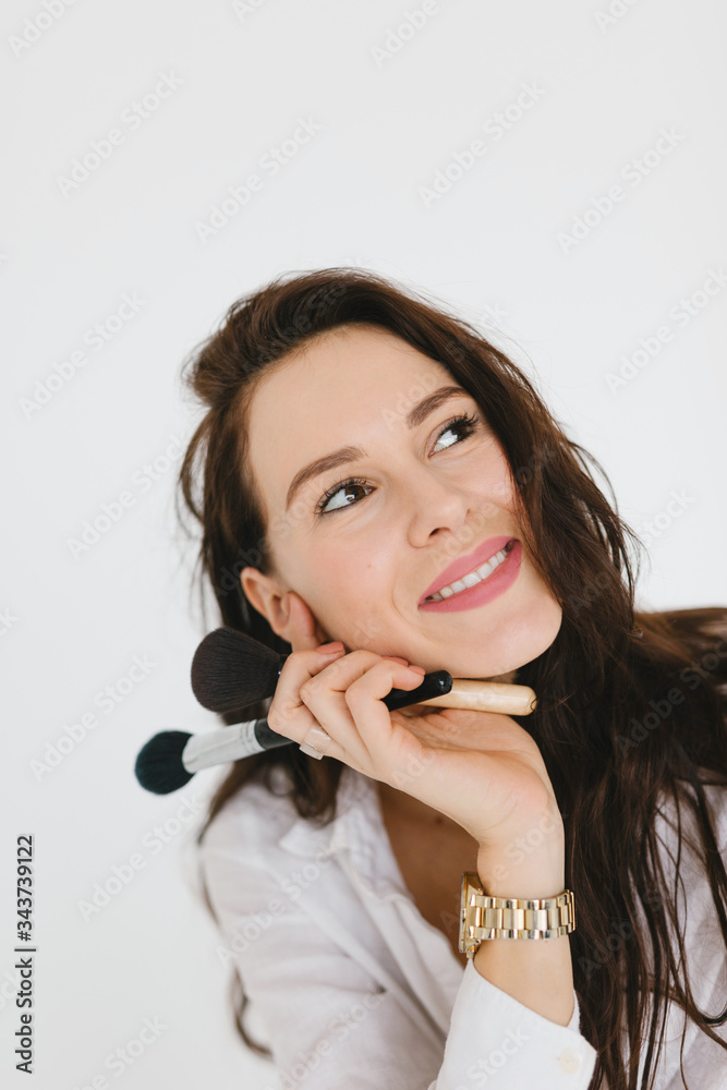 Young woman does makeup. Portrait of a pretty brunette girl with long hair. Cosmetic and wellness concept. Young woman does makeup. Portrait of a pretty brunette girl with long hair. Cosmetic and wellness concept.