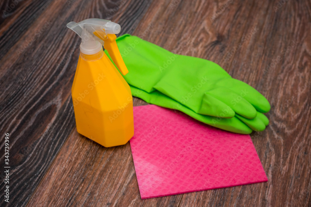 Close-up of a spray bottle, rubber gloves and a wet rag lying on the floor. The concept of disinfection of premises, the prevention of viral and bacterial diseases. Cleaning wooden surfaces. Close-up of a spray bottle, rubber gloves and a wet rag lying on the floor. The concept of disinfection of premises, the prevention of viral and bacterial diseases. Cleaning wooden surfaces.
