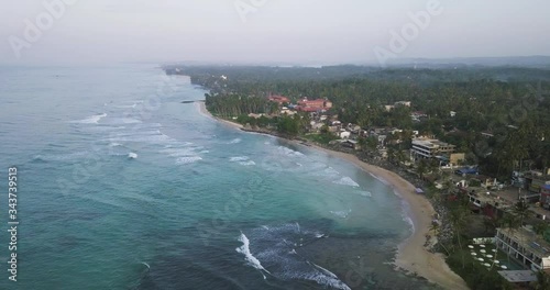 Scenic aerial view above coastline of Sri Lanka with waving sea and tourisitc buildings along the coast. photo