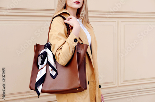 Fashionwoman in autumn outfit with big brown bag and scarf. photo