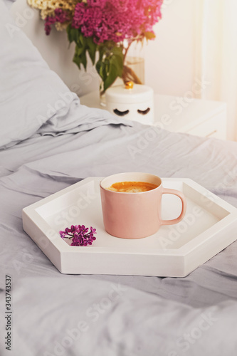 Tray with fresh cup of coffee and macarons dessert standing on the bed