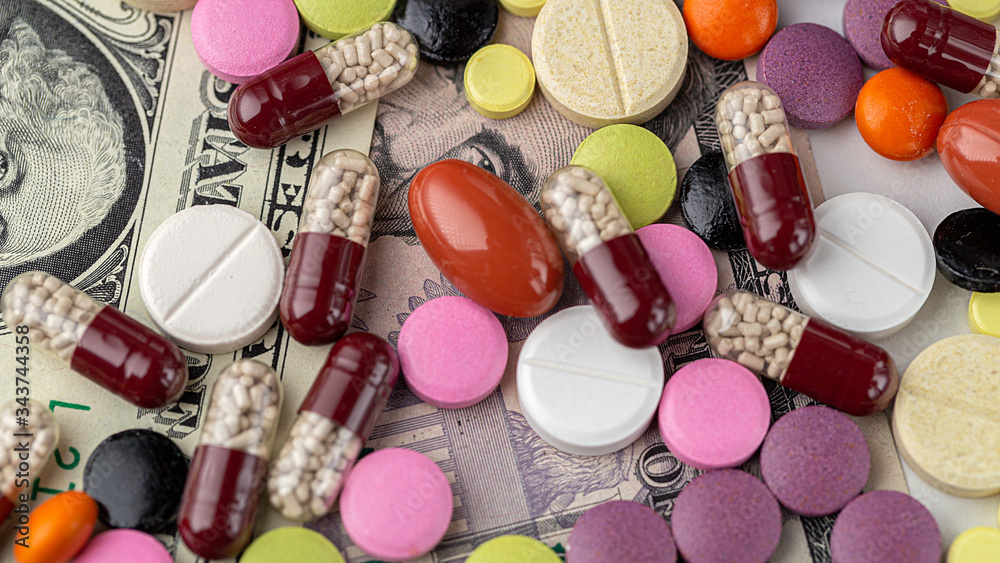The concept of making money on medicines. Multicolored drugs on a background of dollars. Different remedy, pills, capsule, antibiotic and vitamin. The concept of making money on medicines. Multicolored drugs on a background of dollars. Different remedy, pills, capsule, antibiotic and vitamin.