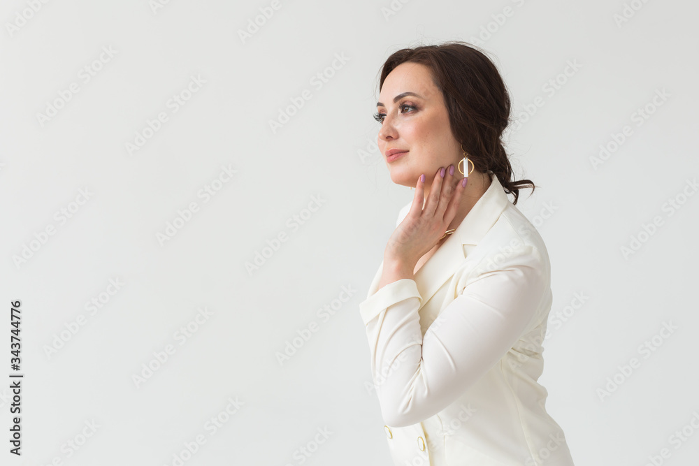 High fashion shoot of young brunette woman with elegant hairstyle in white suit indoors. Business people and trendy style concept. Copy space. High fashion shoot of young brunette woman with elegant hairstyle in white suit indoors. Business people and trendy style concept. Copy space.