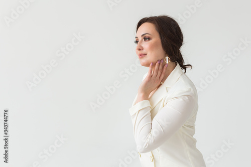 High fashion shoot of young brunette woman with elegant hairstyle in white suit indoors. Business people and trendy style concept. Copy space.
