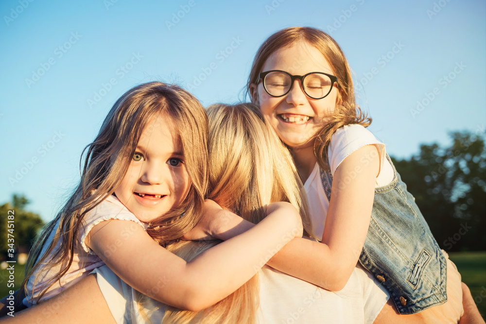 Two little daughters hugging their mother. Mother day concept. Family and motherhood.