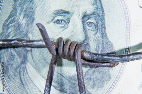 Close up barbed wire against US Dollar bill as symbol of  bribery in politics, business, diplomacy. Horizontal image.