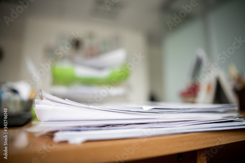 Pile of documents on desk stack up high waiting to be managed.