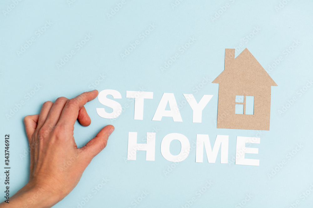 Letters for stay home message being placed by hand on a blue surface Letters for stay home message being placed by hand on a blue surface