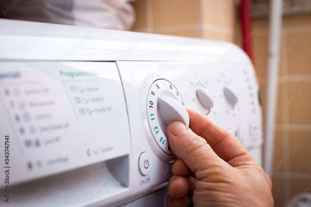 Human hand using knob on home washing machine control panel