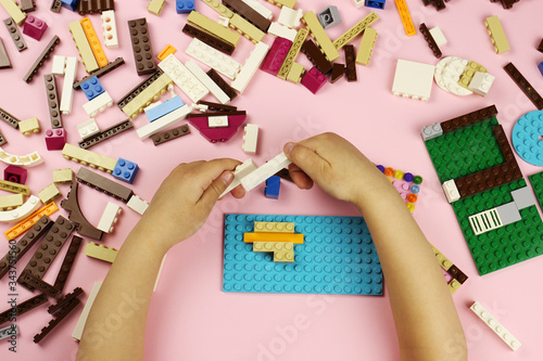 Child playing with colored blocks on a pink background photo