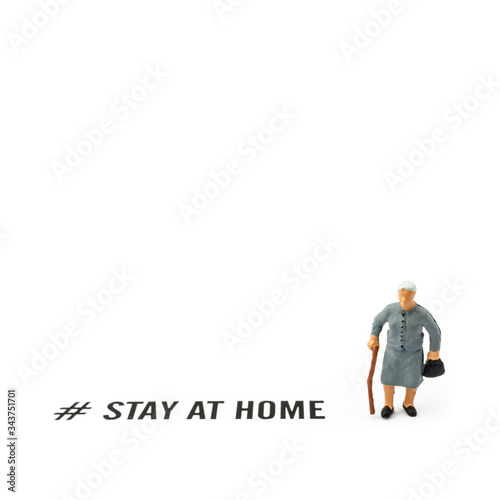 Old woman and coronavirus outbreak. Small figurine and text STAY AT HOME on white background.