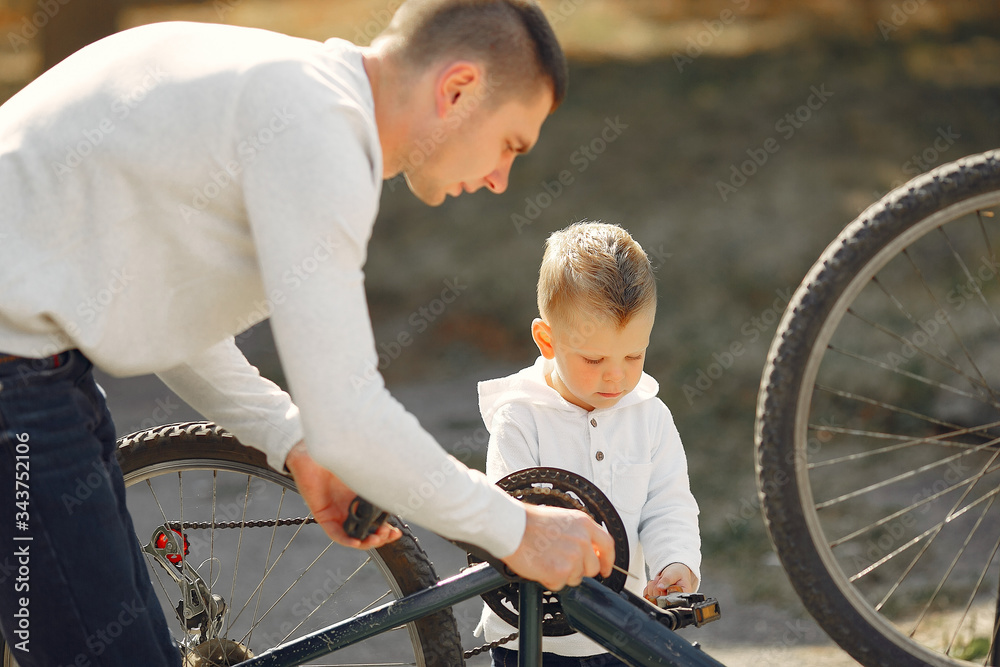 Obraz premium Family in a park. Father with son. People repare the bike.