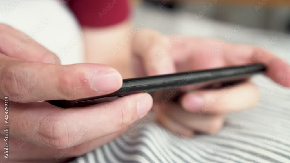 Hands close up playing a mobile game on smartphone at home. Young gamer using mobile phone for online game. Hands close up playing a mobile game on smartphone at home. Young gamer using mobile phone for online game.