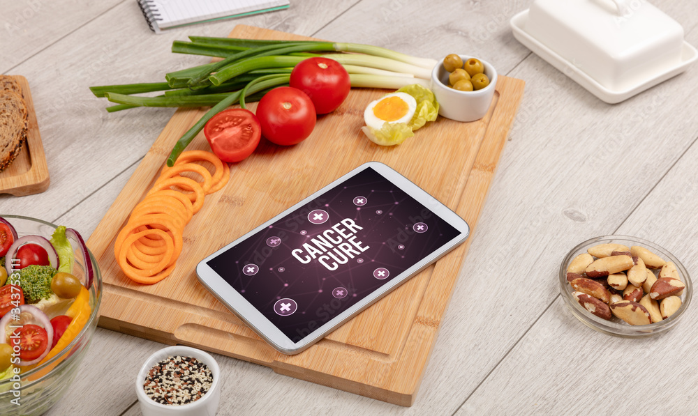 CANCER CURE concept in tablet pc with healthy food around, top view CANCER CURE concept in tablet pc with healthy food around, top view