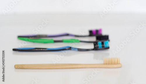 Organic biodegradable bamboo toothbrush with cotton buds in the blurred background.