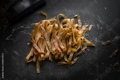 Process of making homemade wholewheat pasta in a kitchen with pasta sheet roller. Close up view. Dark photography