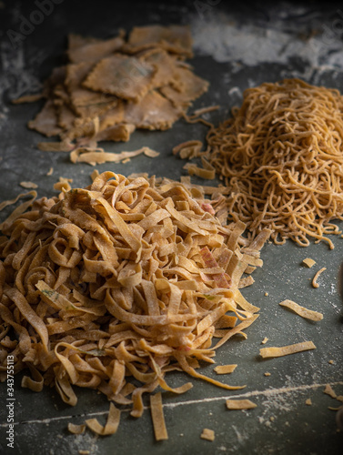 Process of making homemade wholewheat pasta in a kitchen with pasta sheet roller. Close up view. Dark photography
