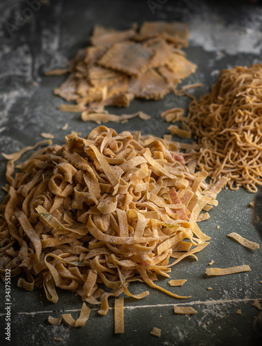 Process of making homemade wholewheat pasta in a kitchen with pasta sheet roller. Close up view. Dark photography