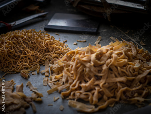 Process of making homemade wholewheat pasta in a kitchen with pasta sheet roller. Close up view. Dark photography