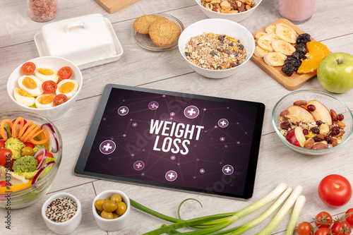 WEIGHT LOSS concept in tablet pc with healthy food around, top view