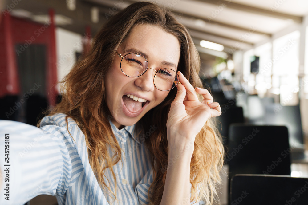 Image of funny beautiful woman winking and taking selfie