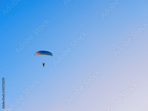 Paraglider flies on a paraglider over the city on a warm summer evening