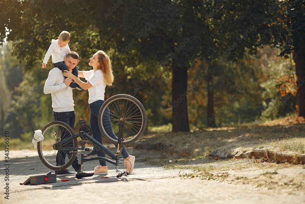 Obraz premium Family in a park. Father and mother with son. People repare the bike.