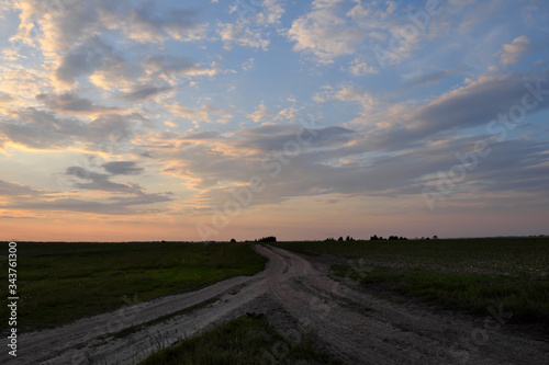 Fork of two country roads in the evening in the field. Evening landscape.