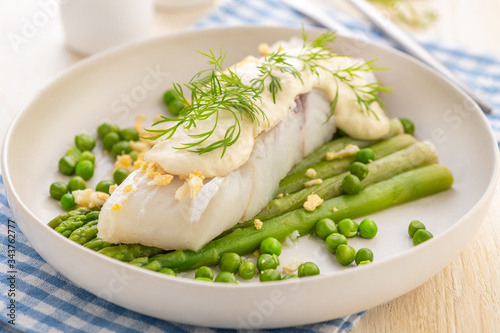 Steamed white fish fillet with asparagus and green peas and thick sauce.