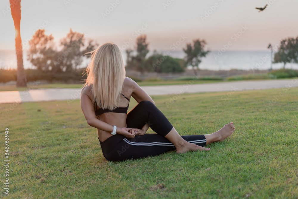 Fit slim woman morning or evening yoga pilates training near sea in park. bodyweight Exercises outdoor workout in sunset light rays. healthy lifestyle every day sport without gym concept