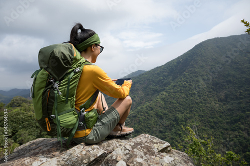 Successful hiker using smartphone on mountain top cliff edge photo