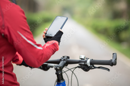 Cyclist use smartphone for navigation when riding mountain bike on forest trail