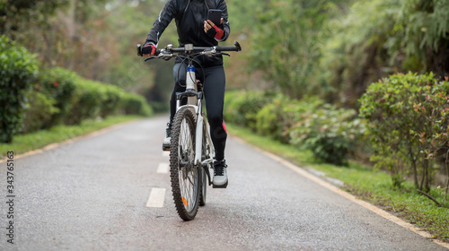 Cyclist use smartphone when riding mountain bike on forest trail